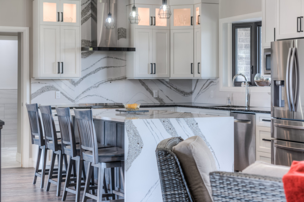 Example of a transitional eat-in kitchen design with shaker cabinets, white cabinets, stainless steel appliances and an island