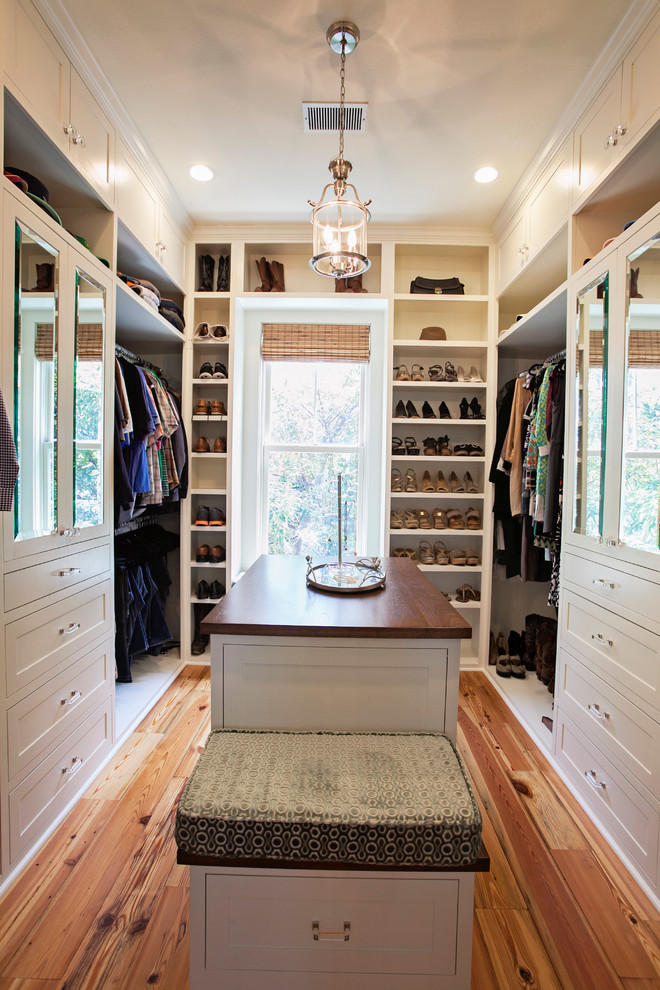 Mid-sized transitional gender-neutral dressing room in Atlanta with white cabinets, medium hardwood floors and shaker cabinets.