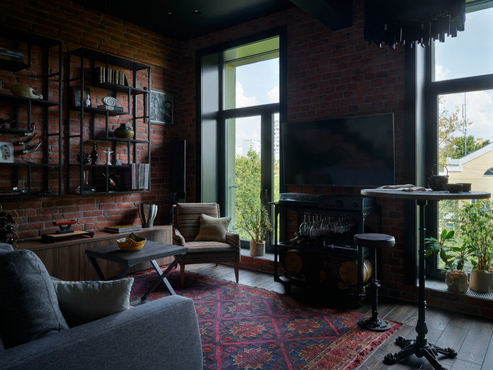 Immagine di un soggiorno industriale di medie dimensioni con libreria, pareti marroni, parquet scuro, TV a parete e pareti in mattoni