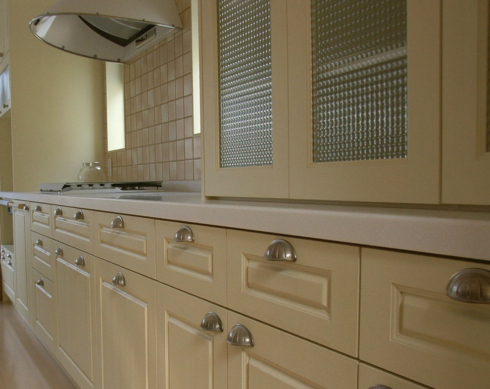 Photo of a mid-sized traditional galley kitchen pantry in Osaka with raised-panel cabinets, yellow cabinets, solid surface benchtops, white appliances, no island, white benchtop and a drop-in sink.
