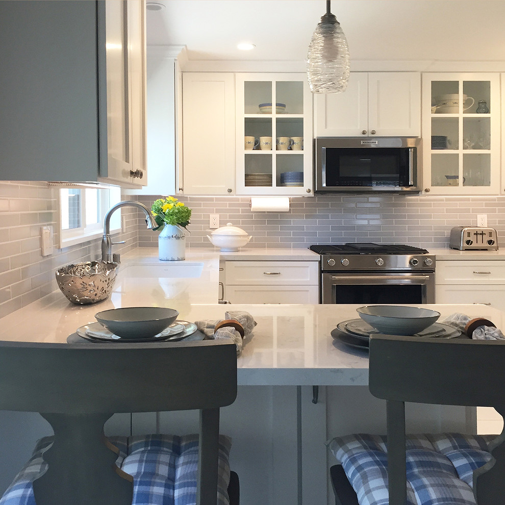 Photo of a mid-sized transitional u-shaped kitchen in Los Angeles with a single-bowl sink, shaker cabinets, white cabinets, quartz benchtops, grey splashback, ceramic splashback, stainless steel appliances, a peninsula and multi-coloured benchtop.
