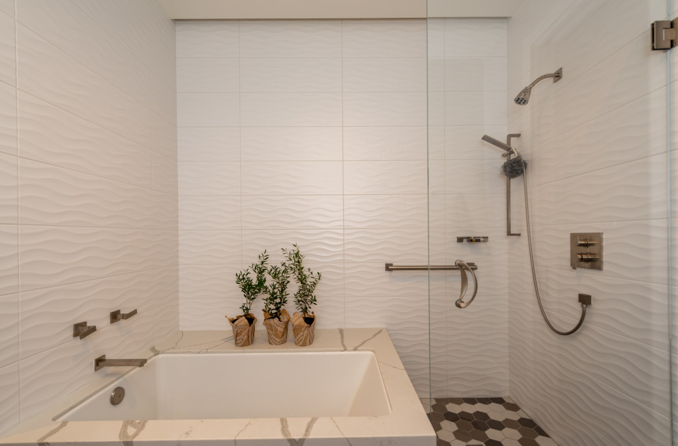 This is an example of a mid-sized country kids bathroom in San Francisco with flat-panel cabinets, distressed cabinets, an undermount tub, a shower/bathtub combo, a two-piece toilet, white tile, porcelain tile, grey walls, mosaic tile floors, an undermount sink, engineered quartz benchtops, grey floor, a hinged shower door, white benchtops, a single vanity and a built-in vanity.