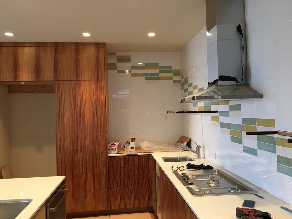 Large contemporary l-shaped open plan kitchen in San Francisco with an undermount sink, flat-panel cabinets, medium wood cabinets, quartzite benchtops, multi-coloured splashback, subway tile splashback, stainless steel appliances, light hardwood floors, with island and brown floor.