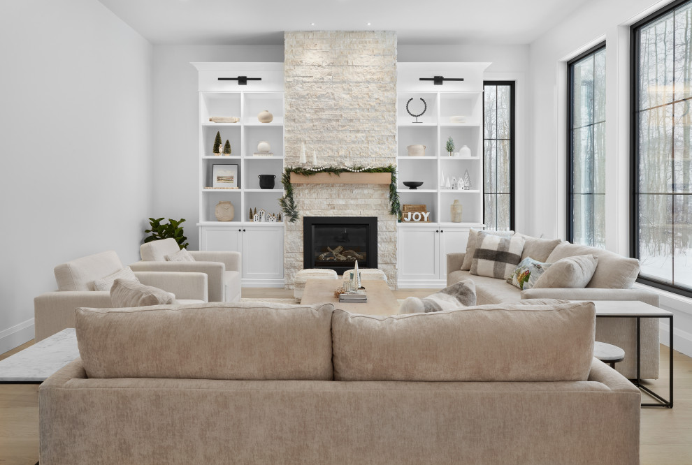 Large contemporary open plan living room in Edmonton with grey walls, light hardwood flooring, a standard fireplace, a brick fireplace surround and brown floors.