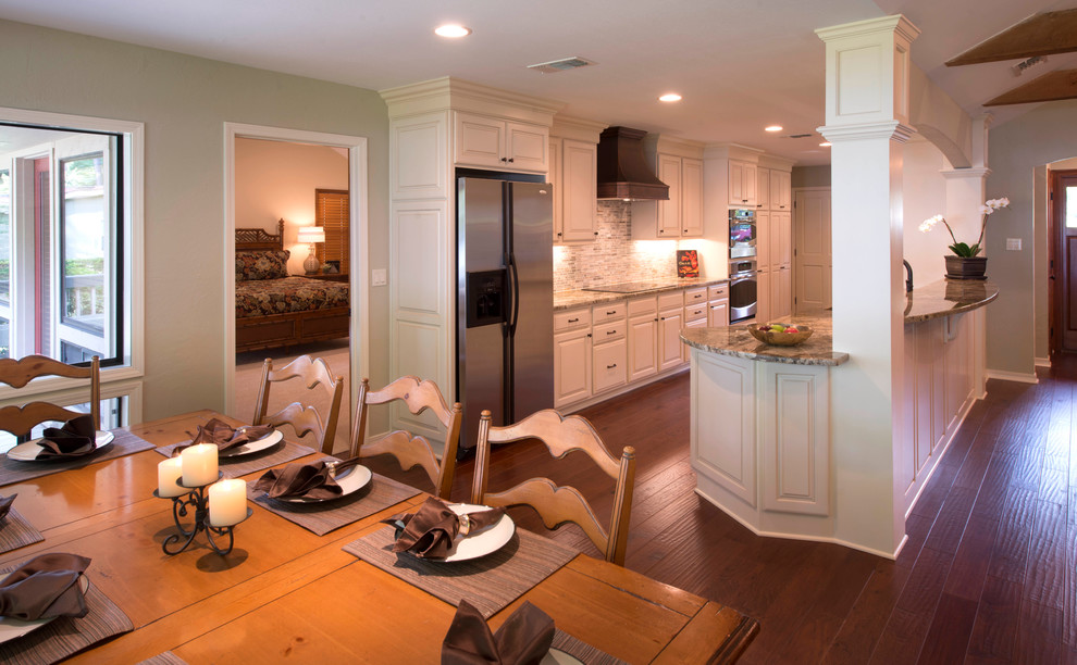 Example of a transitional galley open concept kitchen design in New Orleans with an undermount sink, raised-panel cabinets, white cabinets, granite countertops, gray backsplash, mosaic tile backsplash, stainless steel appliances and engineered wood floors