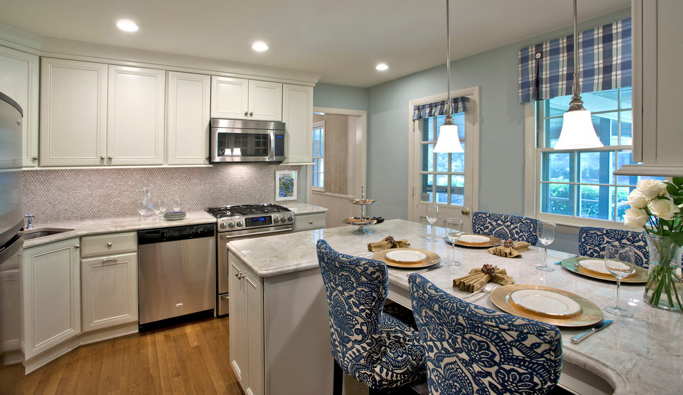 Inspiration for a mid-sized transitional l-shaped light wood floor and brown floor eat-in kitchen remodel in Baltimore with recessed-panel cabinets, white cabinets, marble countertops, a peninsula, an undermount sink, white backsplash, mosaic tile backsplash and stainless steel appliances