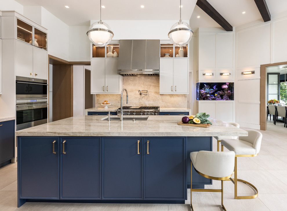 Inredning av ett klassiskt stort blå blått kök, med en enkel diskho, skåp i shakerstil, blå skåp, bänkskiva i kvartsit, beige stänkskydd, en köksö och beiget golv