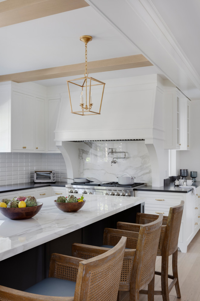 Inspiration for a traditional u-shaped open plan kitchen in Boston with a single-bowl sink, recessed-panel cabinets, white cabinets, soapstone benchtops, white splashback, subway tile splashback, stainless steel appliances, light hardwood floors, with island, black benchtop and exposed beam.
