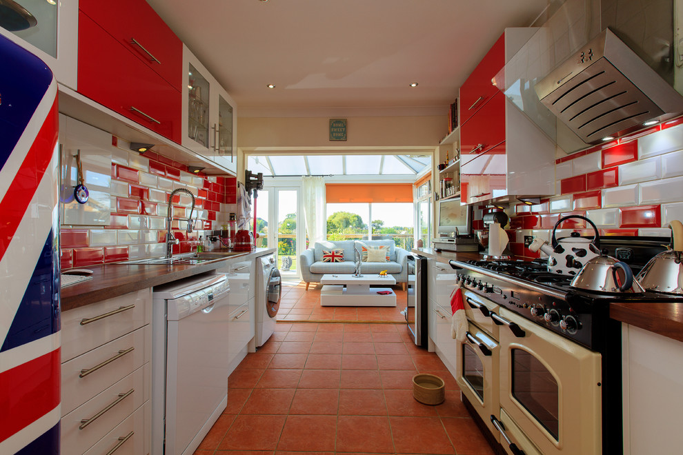 Large eclectic galley kitchen in Sussex with a drop-in sink, red cabinets, wood benchtops, red splashback, subway tile splashback and with island.
