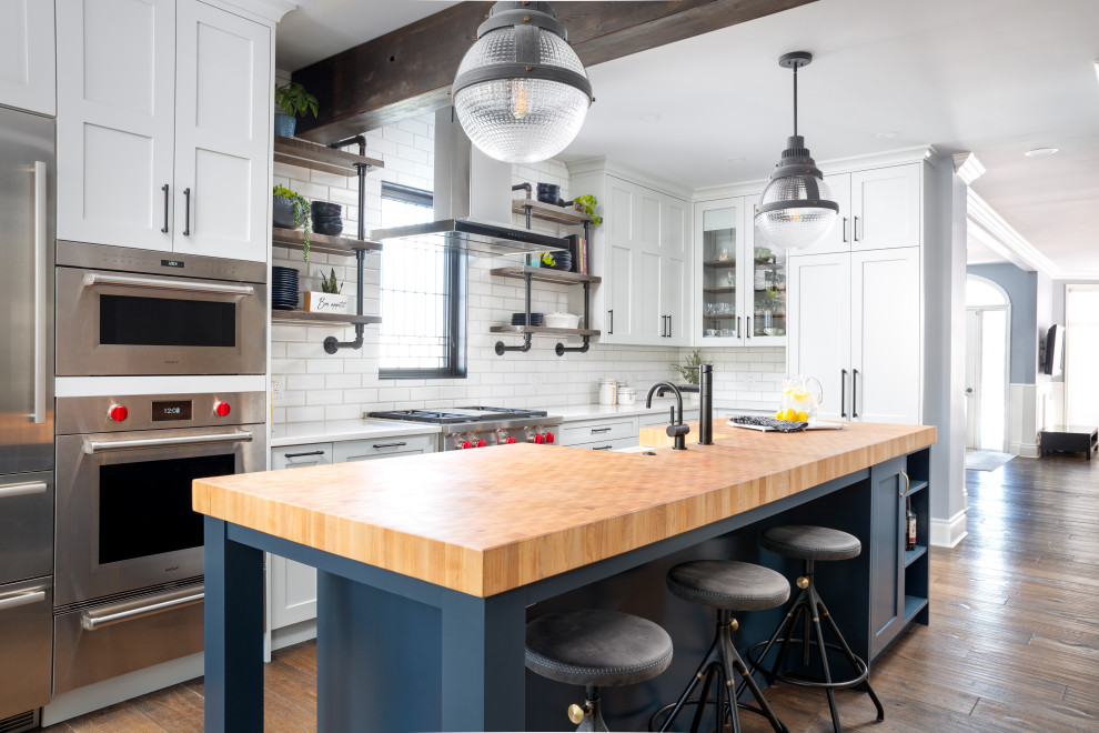 Inspiration for a large transitional u-shaped dark wood floor and brown floor eat-in kitchen remodel in Calgary with a farmhouse sink, shaker cabinets, gray cabinets, wood countertops, white backsplash, porcelain backsplash, stainless steel appliances, an island and white countertops