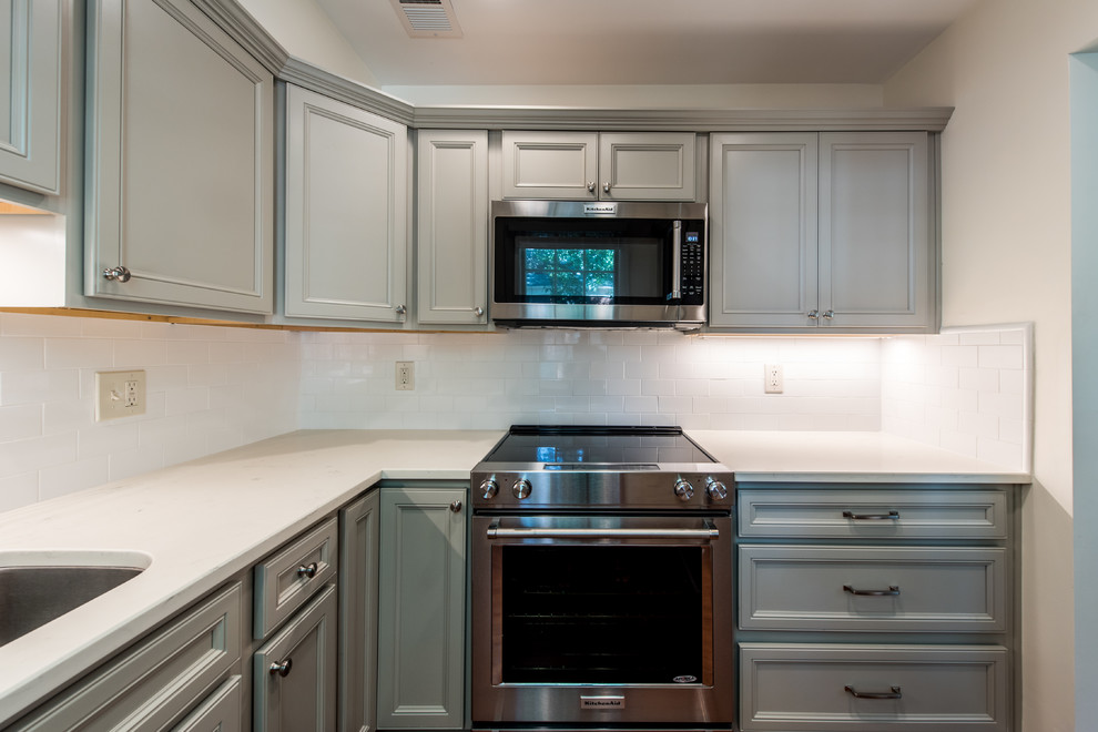 Example of a small transitional l-shaped vinyl floor and brown floor eat-in kitchen design in DC Metro with an undermount sink, shaker cabinets, gray cabinets, quartz countertops, white backsplash, porcelain backsplash, stainless steel appliances and no island