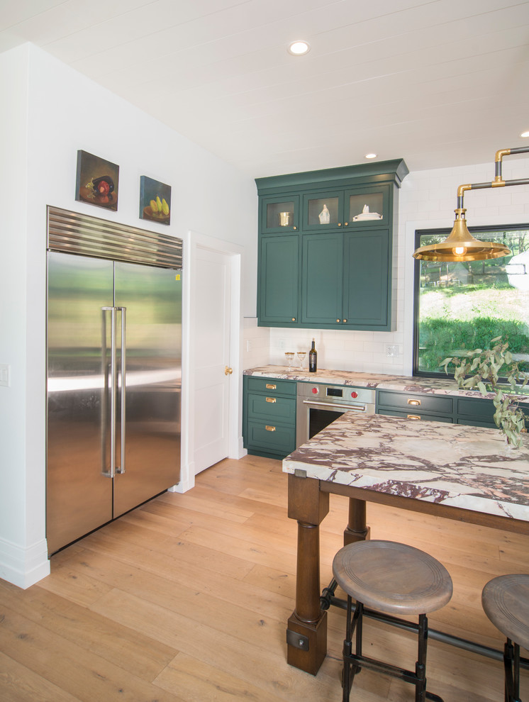 Inspiration for a large country galley eat-in kitchen in San Francisco with a drop-in sink, flat-panel cabinets, green cabinets, marble benchtops, white splashback, ceramic splashback, stainless steel appliances, medium hardwood floors, with island, brown floor and white benchtop.