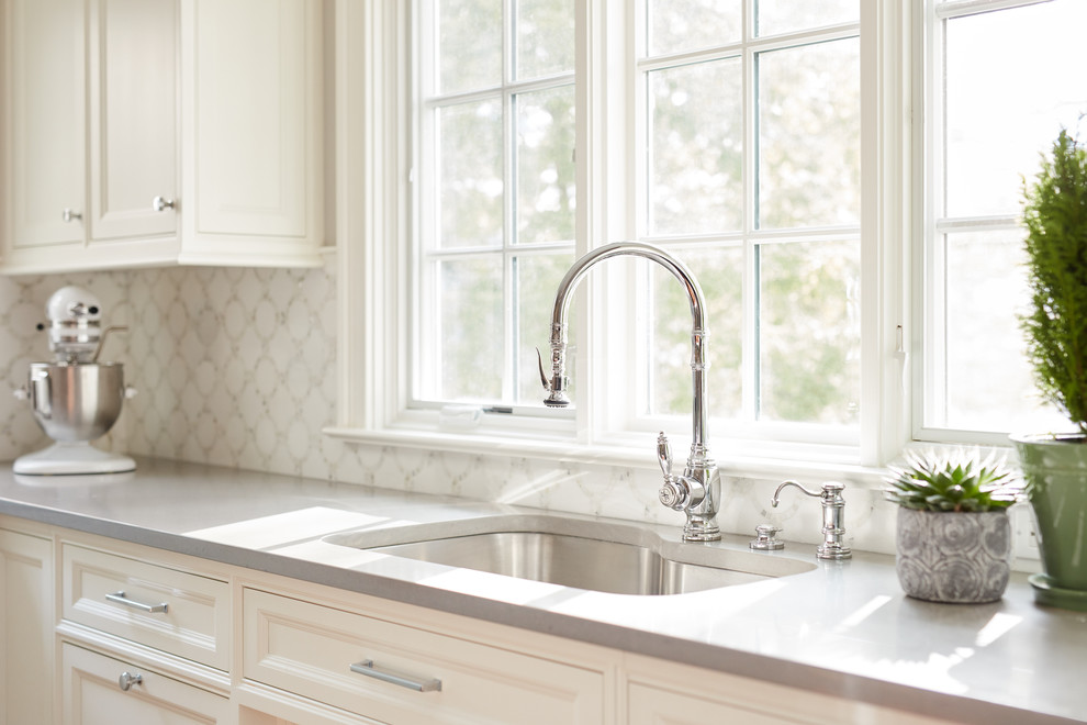 Example of a mid-sized transitional l-shaped brown floor and medium tone wood floor eat-in kitchen design in Boston with paneled appliances, an island, recessed-panel cabinets, white cabinets, white backsplash, an undermount sink, quartzite countertops and gray countertops