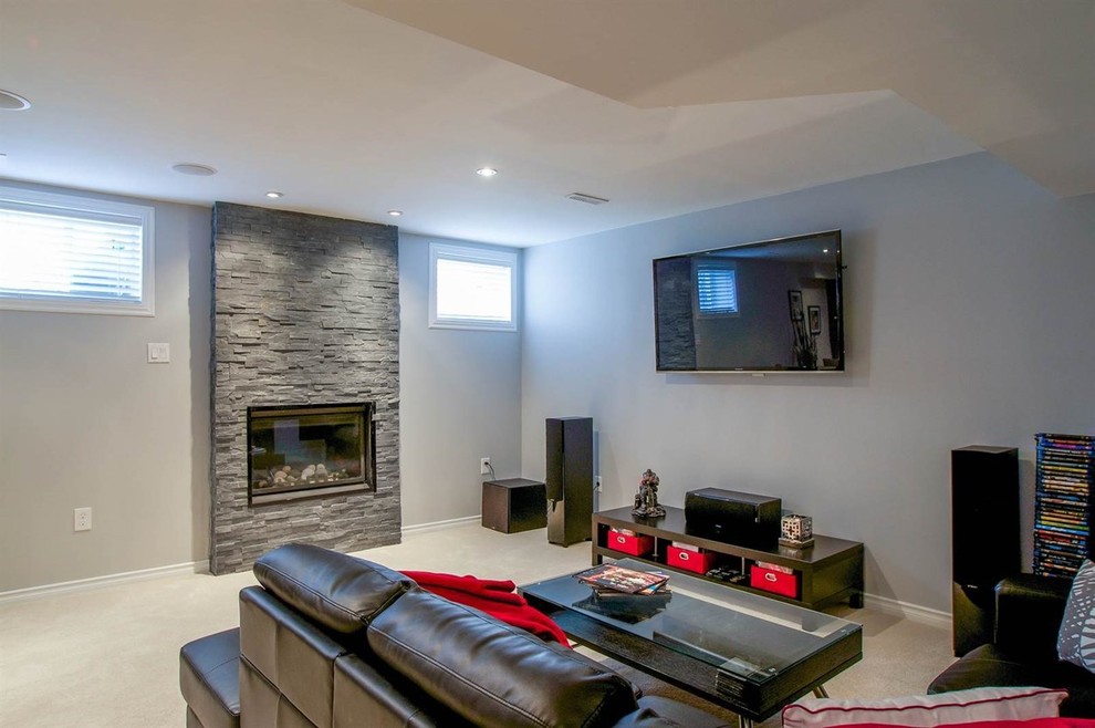 Inspiration for a mid-sized modern look-out basement in Toronto with grey walls, carpet, a standard fireplace and a stone fireplace surround.