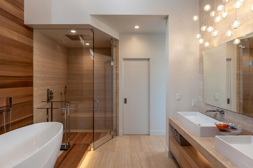 This is an example of a large contemporary master bathroom in San Francisco with open cabinets, a freestanding tub, a corner shower, beige tile, porcelain tile, white walls, porcelain floors, a vessel sink, wood benchtops, beige floor, a hinged shower door and beige benchtops.