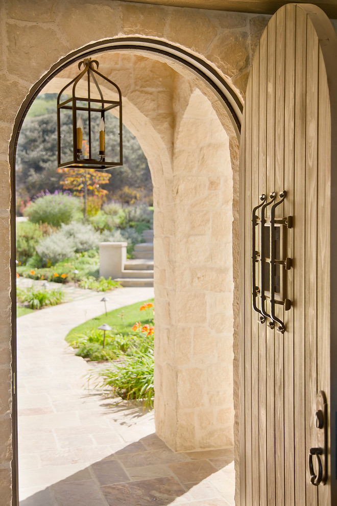 Design ideas for a large mediterranean front door in Los Angeles with beige walls, limestone floors, a single front door and a medium wood front door.