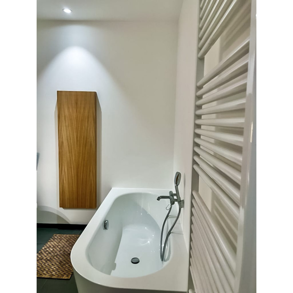 Bild på ett mellanstort funkis vit vitt badrum med dusch, med släta luckor, skåp i ljust trä, ett undermonterat badkar, en hörndusch, en vägghängd toalettstol, vita väggar, skiffergolv, ett väggmonterat handfat, träbänkskiva, grått golv och dusch med skjutdörr
