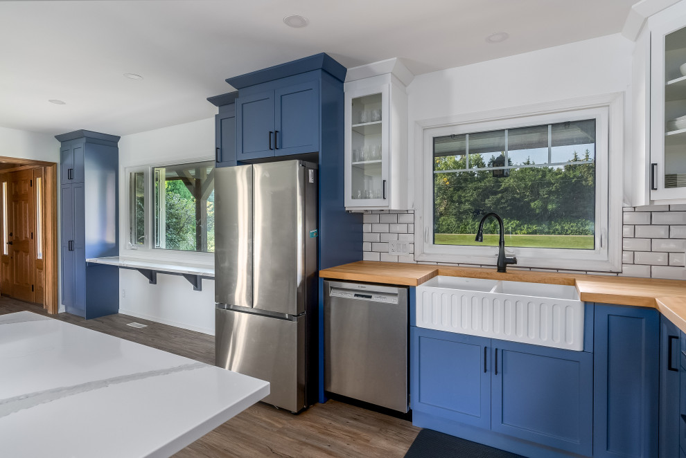 Transitional kitchen photo in Edmonton with shaker cabinets, blue cabinets, quartzite countertops, subway tile backsplash, stainless steel appliances, an island and white countertops