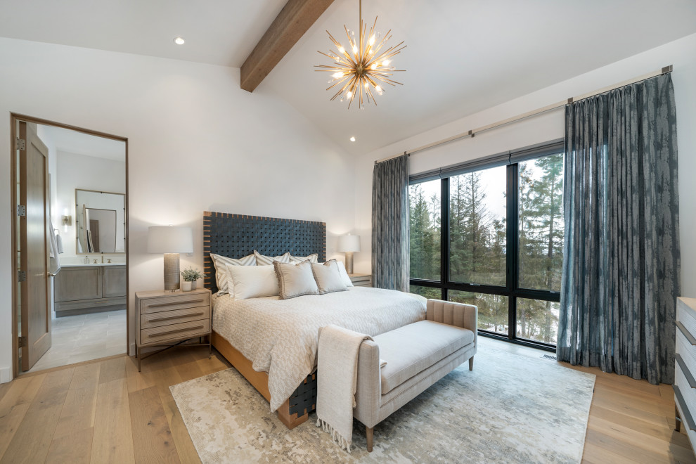 Example of a large transitional master medium tone wood floor, brown floor and vaulted ceiling bedroom design with white walls