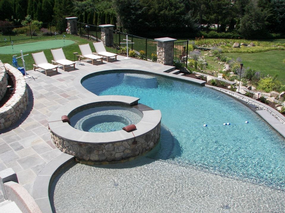 Example of a large mountain style backyard stone and custom-shaped infinity hot tub design in Boston