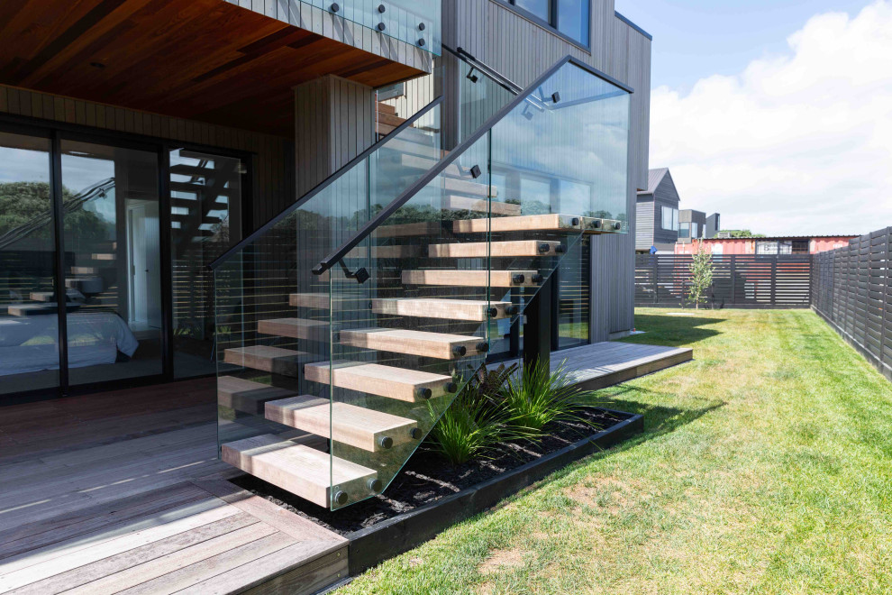 Ejemplo de escalera suspendida minimalista de tamaño medio sin contrahuella con escalones de madera y barandilla de metal