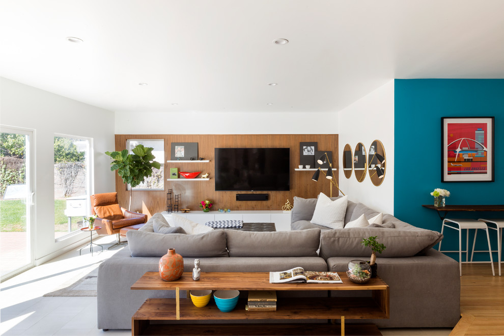 Inspiration for a mid-sized midcentury open concept family room in Los Angeles with white walls, limestone floors, a wall-mounted tv and beige floor.