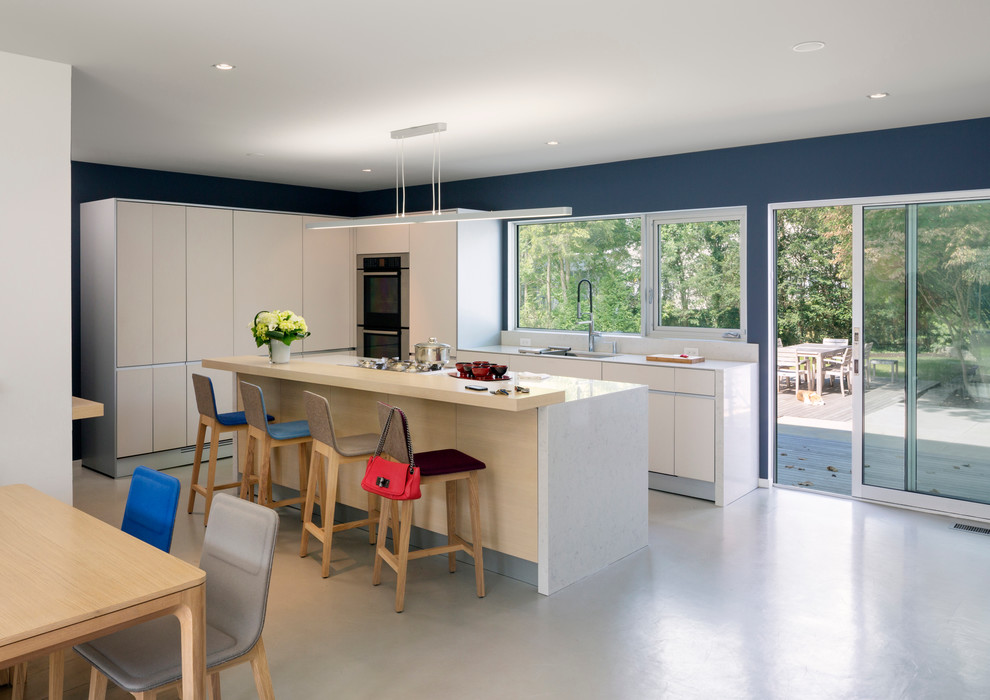Contemporary l-shaped eat-in kitchen in San Francisco with flat-panel cabinets, white cabinets, stainless steel appliances, with island and grey floor.