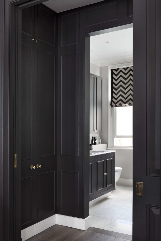 Photo of a large contemporary gender-neutral walk-in wardrobe in London with open cabinets, black cabinets, plywood floors, brown floor and coffered.
