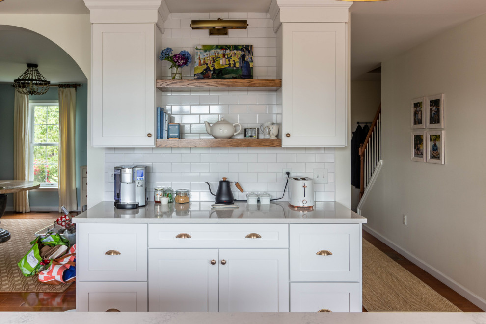 Inspiration for a mid-sized transitional l-shaped medium tone wood floor and brown floor open concept kitchen remodel with an undermount sink, shaker cabinets, white cabinets, quartzite countertops, white backsplash, ceramic backsplash, white appliances, an island and white countertops