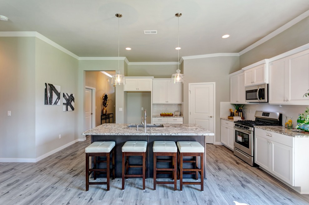 Small transitional l-shaped laminate floor and gray floor open concept kitchen photo in Seattle with an undermount sink, shaker cabinets, white cabinets, quartz countertops, white backsplash, subway tile backsplash, stainless steel appliances, an island and gray countertops