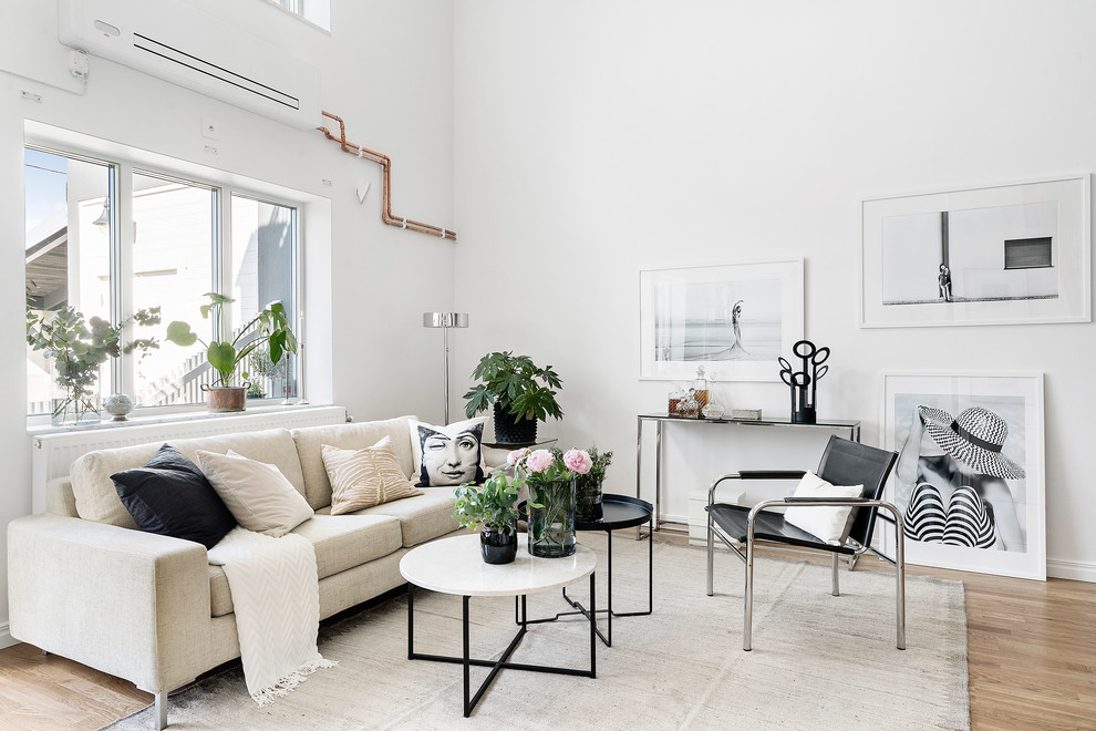 This is an example of a scandinavian living room in Copenhagen with white walls, light hardwood floors and beige floor.