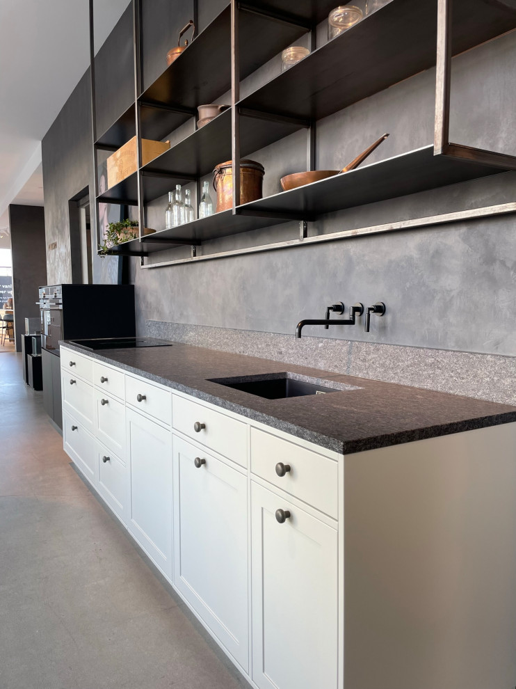 Lantlig inredning av ett avskilt, mellanstort grå linjärt grått kök, med en undermonterad diskho, skåp i shakerstil, beige skåp, granitbänkskiva, grått stänkskydd, integrerade vitvaror, betonggolv och grått golv