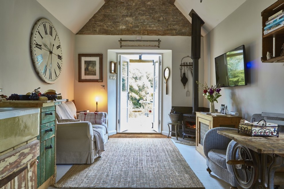 Kleines, Offenes Uriges Wohnzimmer mit grauer Wandfarbe, Linoleum, Kaminofen, gefliester Kaminumrandung, TV-Wand und grauem Boden in Gloucestershire