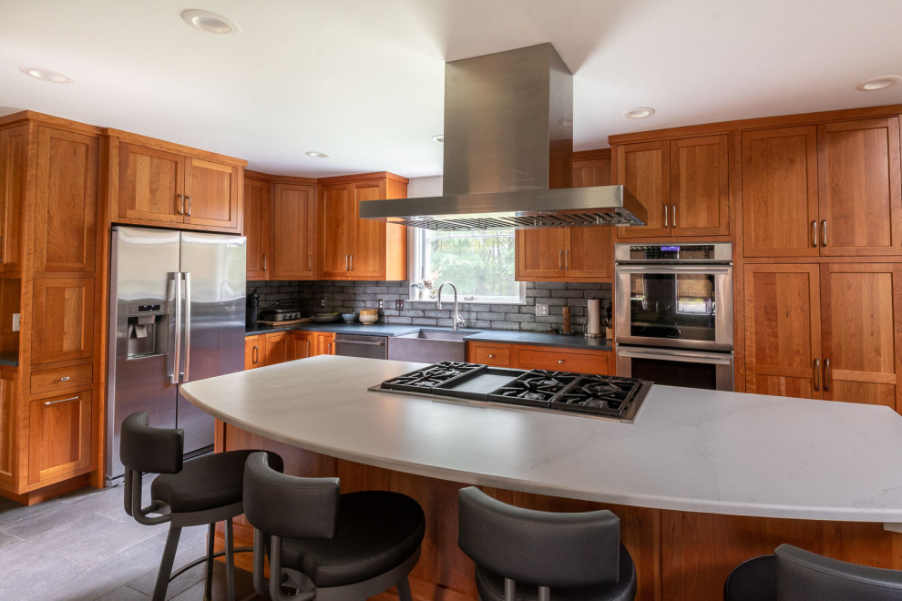 Eat-in kitchen - large transitional l-shaped porcelain tile and gray floor eat-in kitchen idea in Boston with a farmhouse sink, shaker cabinets, medium tone wood cabinets, quartz countertops, gray backsplash, porcelain backsplash, stainless steel appliances, an island and white countertops
