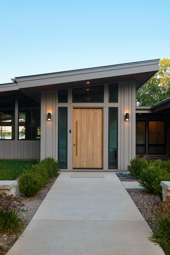 Design ideas for an expansive contemporary front door in Grand Rapids with a pivot front door and a light wood front door.