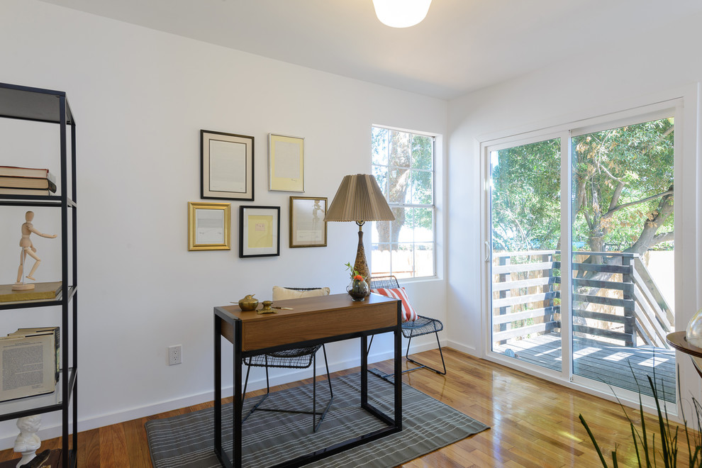 Example of a trendy freestanding desk light wood floor study room design in Los Angeles with white walls