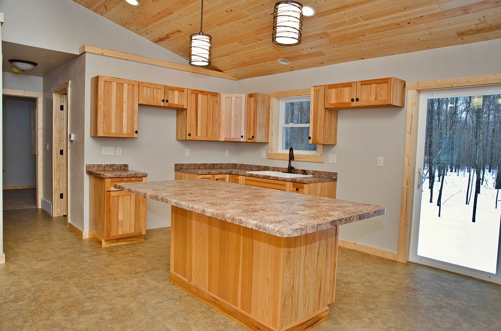 Mid-sized mountain style l-shaped linoleum floor and brown floor open concept kitchen photo with a drop-in sink, recessed-panel cabinets, light wood cabinets, laminate countertops and an island