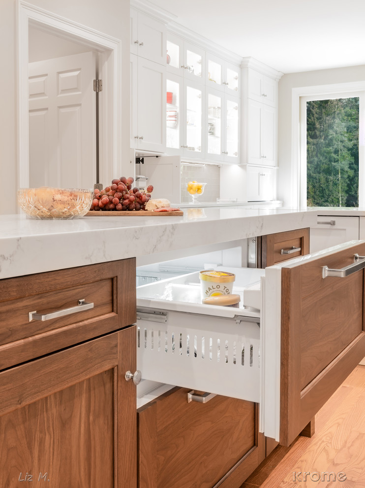 Example of a large transitional u-shaped light wood floor and brown floor eat-in kitchen design in Boston with an undermount sink, recessed-panel cabinets, white cabinets, quartz countertops, gray backsplash, glass tile backsplash, stainless steel appliances, an island and white countertops