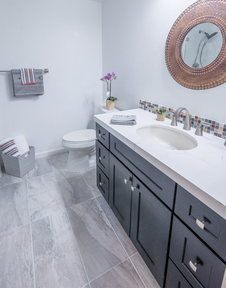 This is an example of a mid-sized transitional 3/4 bathroom in San Francisco with recessed-panel cabinets, dark wood cabinets, an undermount tub, a corner shower, a two-piece toilet, beige tile, blue tile, multi-coloured tile, red tile, glass sheet wall, white walls, ceramic floors, an undermount sink, quartzite benchtops, grey floor and a hinged shower door.