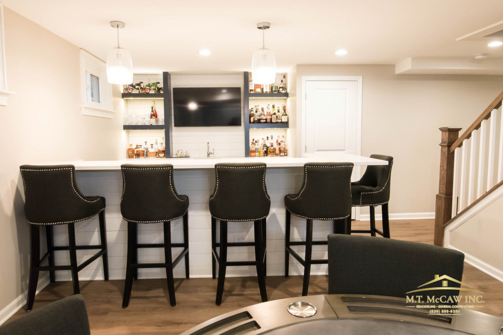Inspiration for a large contemporary underground laminate floor, beige floor and shiplap wall basement remodel in Chicago with a bar and beige walls