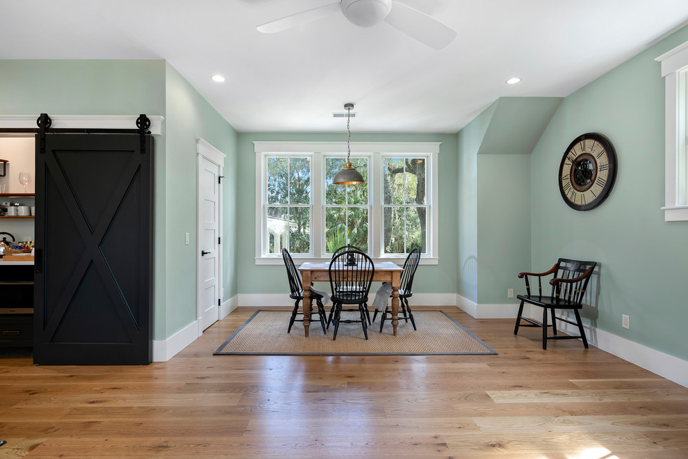 Large beach style dining room in Charleston with medium hardwood floors, brown floor and green walls.