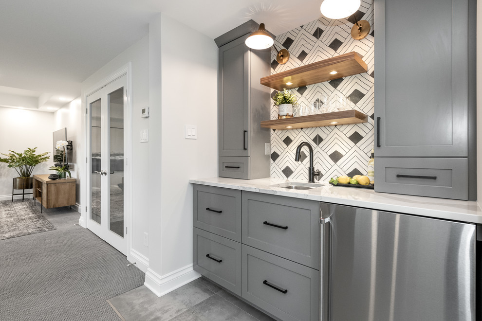 This is an example of a mid-sized transitional single-wall wet bar in Ottawa with an undermount sink, grey cabinets, multi-coloured splashback, porcelain floors, grey floor, white benchtop, shaker cabinets, quartz benchtops and porcelain splashback.