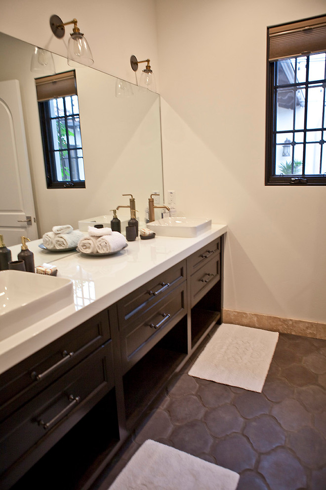 Inspiration for a mid-sized transitional bathroom in San Diego with shaker cabinets, dark wood cabinets, an alcove tub, an alcove shower, a one-piece toilet, beige tile, stone tile, white walls, terra-cotta floors, a vessel sink and marble benchtops.