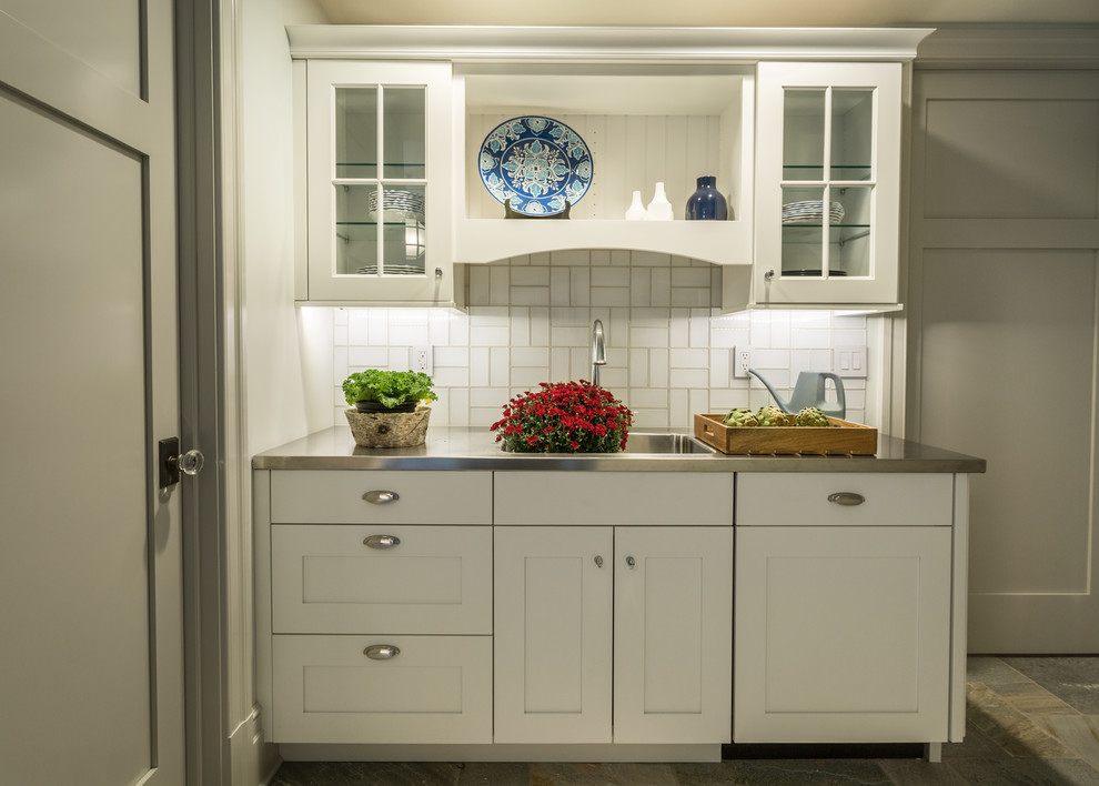 This is an example of a large traditional u-shaped utility room in Milwaukee with a drop-in sink, recessed-panel cabinets, white cabinets, solid surface benchtops, grey walls, porcelain floors and a side-by-side washer and dryer.