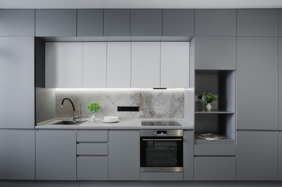 Medium sized contemporary single-wall open plan kitchen in Moscow with a built-in sink, flat-panel cabinets, grey cabinets, grey splashback, stainless steel appliances, laminate floors, no island, beige floors and grey worktops.