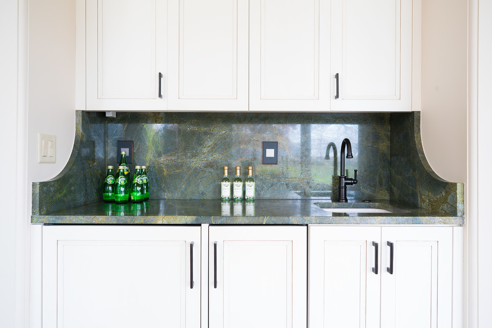 This is an example of a small transitional single-wall wet bar in Philadelphia with an undermount sink, flat-panel cabinets, white cabinets, quartzite benchtops, green splashback, stone slab splashback and limestone floors.