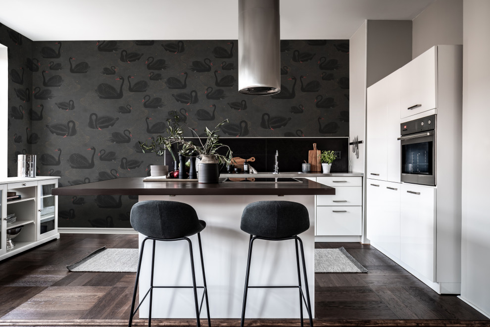 Mid-sized contemporary l-shaped kitchen in Gothenburg with flat-panel cabinets, white cabinets, stainless steel appliances, with island, brown floor and brown benchtop.