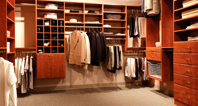 This is an example of a mid-sized traditional gender-neutral walk-in wardrobe in Jacksonville with flat-panel cabinets, medium wood cabinets and carpet.