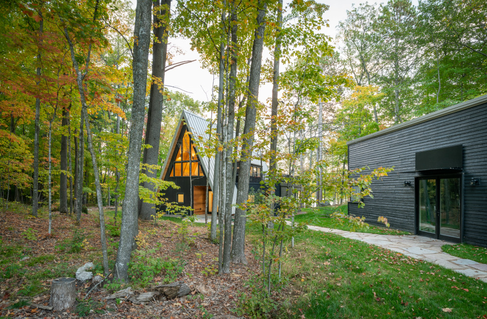 Inspiration för små moderna svarta hus, med blandad fasad, sadeltak och tak i metall