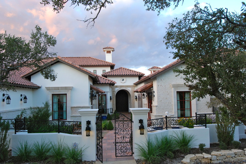 This is an example of an expansive mediterranean two-storey stucco beige house exterior in Austin with a hip roof and a tile roof.